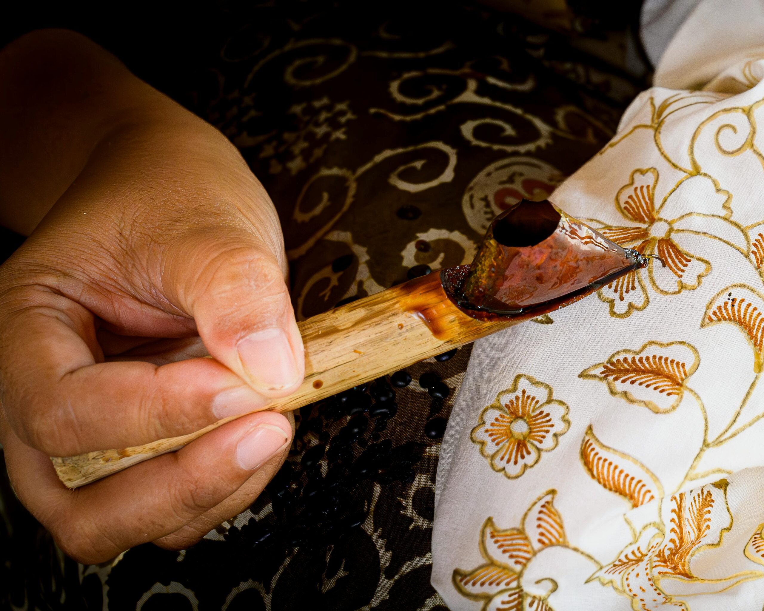 Close-up of a hand crafting traditional batik with hot wax in Jakarta, Indonesia.
